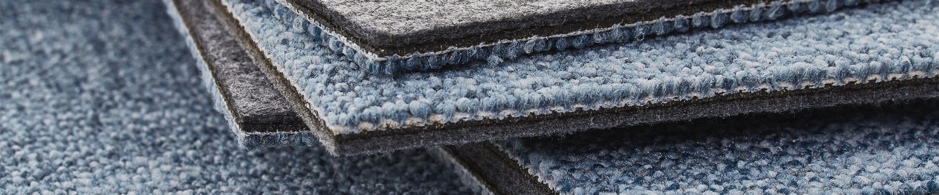 Stack of carpet tiles showcasing the acoustic felt underlay of DESSO SoundMaster 