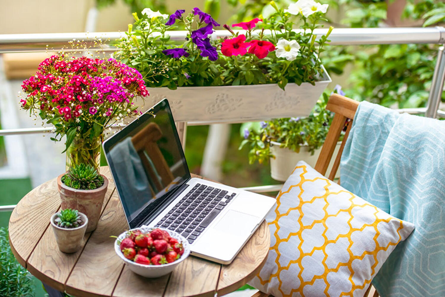 Laptop, fructe si flori pe o masa rotunda in balcon