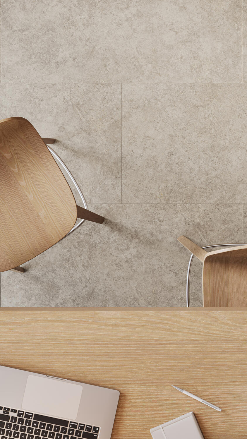 Close up aerial view of a light desk and two chairs on a light grey stone flooring, highlighting iD Naturals
