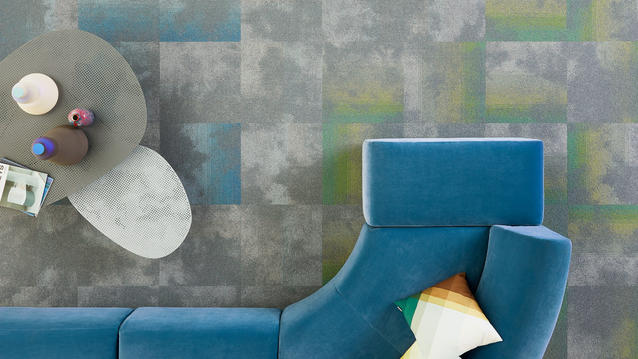 Workspace with Serene DESSO carpet tiles in blue, green, and gray, paired with a modern blue sofa and tables.